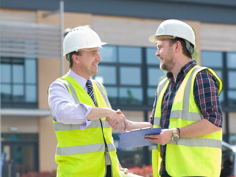 Construction professionals discussing project coordination before work begins on a commercial building site.